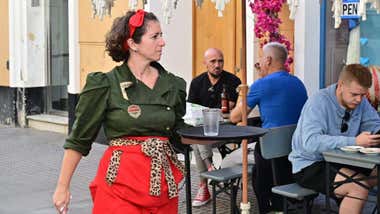 Una mujer atiende en una terraza de un establecmiento hotelero.