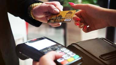 una persona entrega una tarjeta de crédito y otra tiene en su mano un TPV