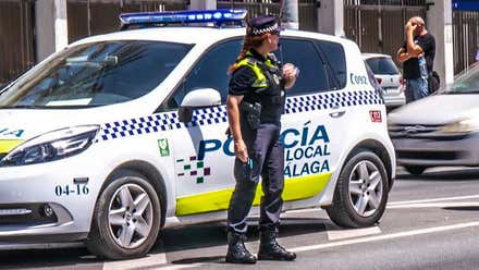 Mujer de la policía municipal de Málaga delante de un coche patrulla