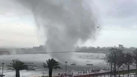Tornado sobre el agua marina entre unas barcas y palmeras