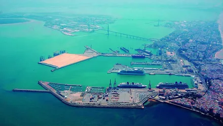 Vista del mar azul con el puente al fondo y la zona portuaria en primer término.