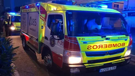 Un camión de bomberos en tono rojizo y amarillo con las sirenas azules encendidas.