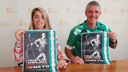 Isabel Butrón y Jonathan Macías presentando el cartel de la prueba deportiva en Chiclana, sostienen el mismo con la mano.