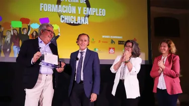 Escenario donde se han entregado la placa. En la imagen están el alcalde de Chiclana, el homenajeado y dos concejalas, destaca el tomo amarillo-anaranjado del fondo.