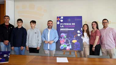 Alumnos y delegado de Cultura de Chiclana junto al cartel de la IV Feria de la Ciencia.
