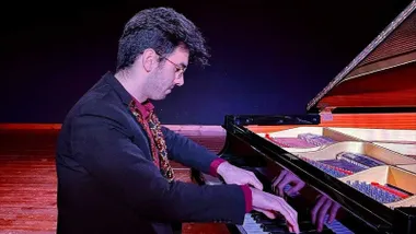El pianista Juan José Sevilla tocando su piano sobre un escenario.