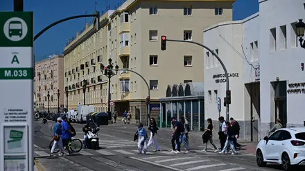 Un grupo de personas cruza un paso de peatones en el Campo del Sur de Cádiz con el cielo completamente azul y despejado