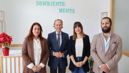 Una pared con el cartel en verde agua "Sonriete Mente", delante de la misma están el alcalde de Chiclana, José María Román, con Noelia Gallego Espinazo y Arancha Clares Pérez, también con el delegado Guillermo Serra.