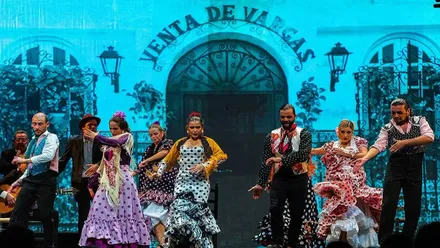 Artistas cantando y bailando en el escenario con el cartel al fondo de "Venta de Vargas".