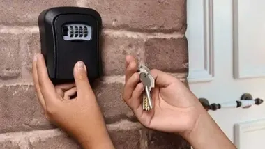 Caja de llaves de una vivienda turística y dos manos sacando las llaves.