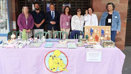 Mesa de color lila y mujeres que forman Afichi así como los representantes municipales, todos en pie.