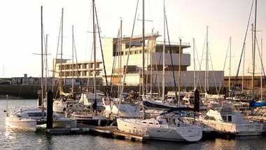 Barcos en la zona del puerto y al fondo una edificación.