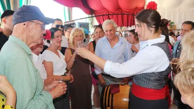 Degustación servida por una chica vestida de corto y varias personas mirando como sirve una copa.