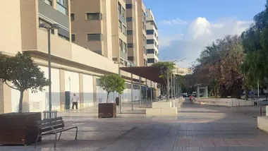 Dos personas caminan por una plaza de Cádiz en una mañana despejada y clara