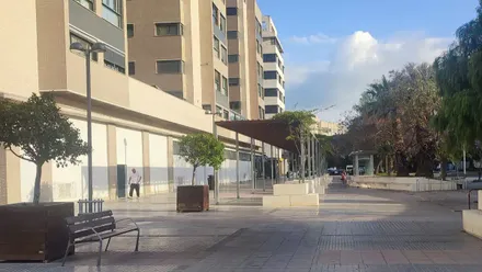 Dos personas caminan por una plaza de Cádiz en una mañana despejada y clara