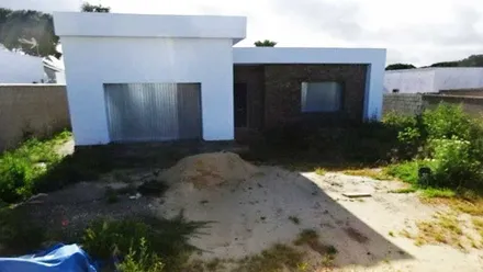 Dos edificaciones en blanco y ladrillo ilegales en un terreno de tierra y poco césped en Chiclana.
