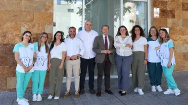 Alcalde y empleados delante de la fachada del Centro Dental Infantil Ávila Bobillo, destacan los tonos tierra y la indumentaria blanca y verde de los empleados.