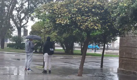 Dos jóvenes se protegen de la lluvia en Cádiz