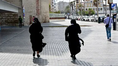 Dos monjas caminan por el Campo de Sur de Cádiz con rachas de viento.