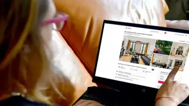 Una mujer visiona en una tablet diferentes pisos a alquilar. Los señala con el dedo.