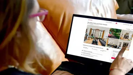 Una mujer visiona en una tablet diferentes pisos a alquilar. Los señala con el dedo.