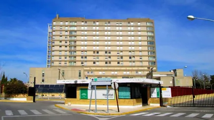 Fachada principal del hospital San Carlos de San Fernando con tonos tierra y el cielo azul.