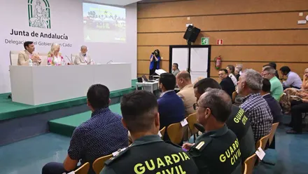 Mercedes Colombo explicando en Plan Infoca 2025 en una mesa y fondo blanco con una proyección a su izquierda.