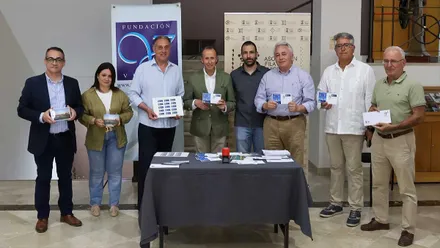 Grupo de personas de Chiclana, alcalde, miembros de Correos y Club Náutico, posan con el matasellos en las manos, en una mesa más objetos conmemorativos.