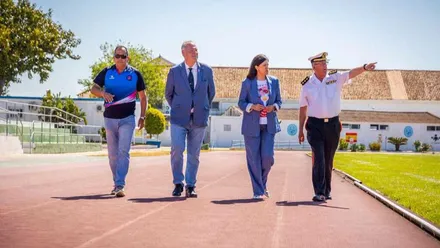 Alcaldesa de San Fernando junto a otras personas caminando por las pistas de atletismo color tierra, al lado derecho el césped del campo.