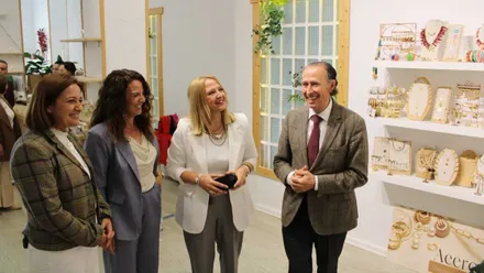 El alcalde José María Román junto a Ana González y Isabel y Carmen Guerrero en el establecimiento nuevo junto a una estantería con productos.