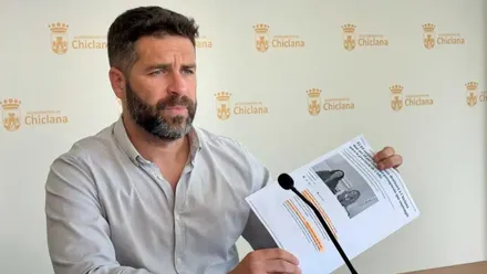 Roberto Palmero, con camisa clara, muestra un documento en las manos.