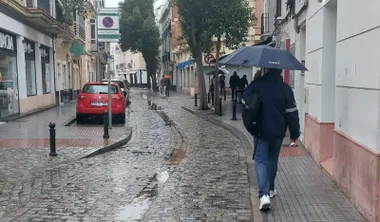 Un hombre camina bajo su paraguas por una calle de Cádiz.