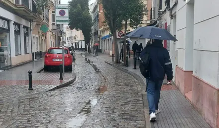 Un hombre camina bajo su paraguas por una calle de Cádiz.