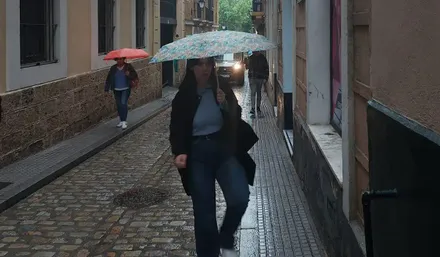 Una joven con un paraguas por las calles de Cádiz