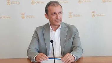 Rodolfo Pérez de chaqueta gris y camisa blanca explicando la consulta apoyado en una mesa de madera.