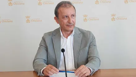 Rodolfo Pérez de chaqueta gris y camisa blanca explicando la consulta apoyado en una mesa de madera.