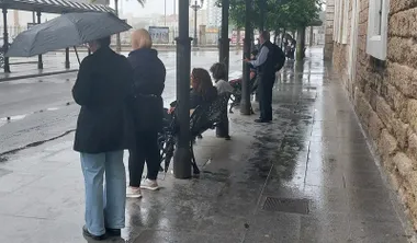 Personas con paraguas en la parada de autobús