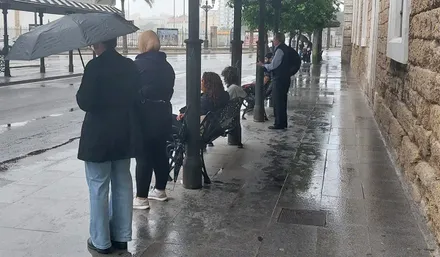 Personas con paraguas en la parada de autobús