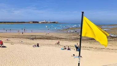 Bandera amarilla en la Playa de la Caleta de Cádiz en bajamar con el Castillo de San Sebastián al fondo