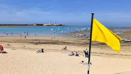 Bandera amarilla en la Playa de la Caleta de Cádiz en bajamar con el Castillo de San Sebastián al fondo