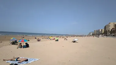 Bañistas y personas usuarias de la playa de La Victoria de Cádiz tomando el sol