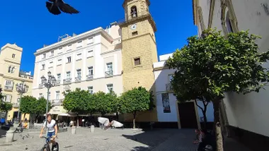 Plaza de San Francisco de Cádiz en un día soleado con un ciclista circulando y espantando a las palomas