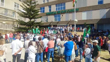 Manifestantes ante la puerta del hospital San Carlos con pancartas y banderas.