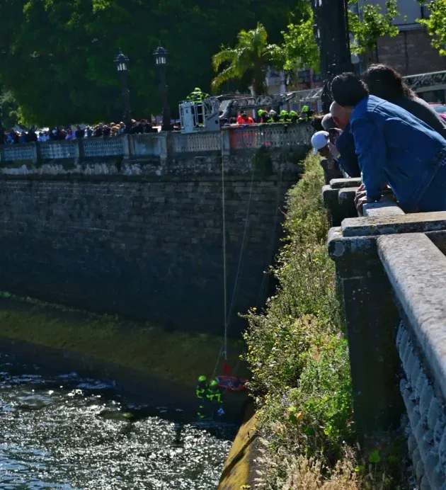 Dos bomberos rescatan en una camilla a la persona que calló por la muralla