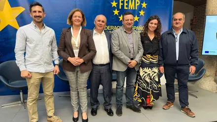 Manuela Pérez posa junto a otros participantes del evento, tras ellos un panel azul y amarillo con la bandera de la CEE.