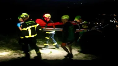 Miembros de rescate con ropas azules y linternas trasladan al parapentista herido en la noche.