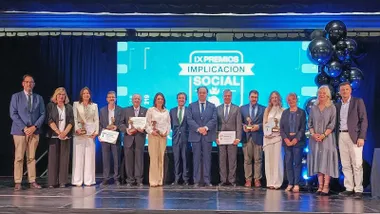 Todos los premiados en el escenario con fondo azul.
