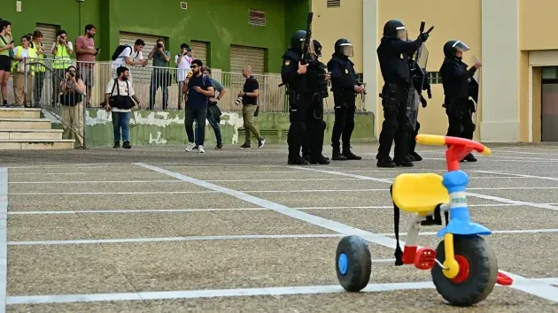 Unidades antidisturbios apostadas en uno de los patios interiores de la Avenida Principal junto a un triciclo infantil