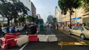 Barricada cortando una calle de Cádiz y manifestantes caminando.