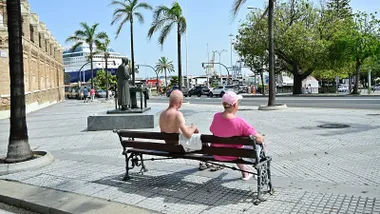 Dos turistas sentados en un banco en la cuesta de las calesas, él sin camiseta
